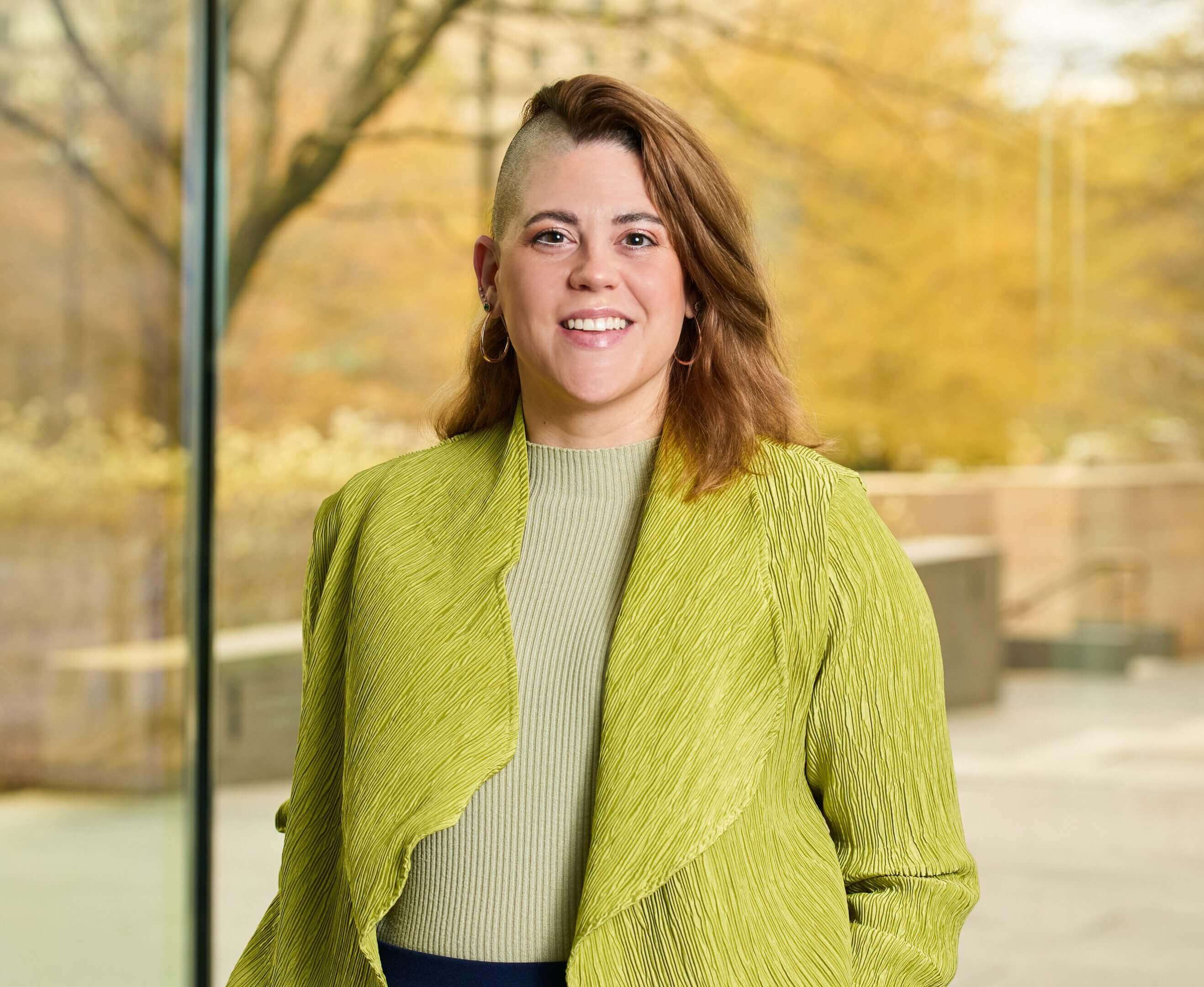 Person in green jacket, outdoor background.