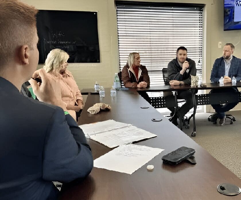 A group meeting in an office conference room with papers on the table.