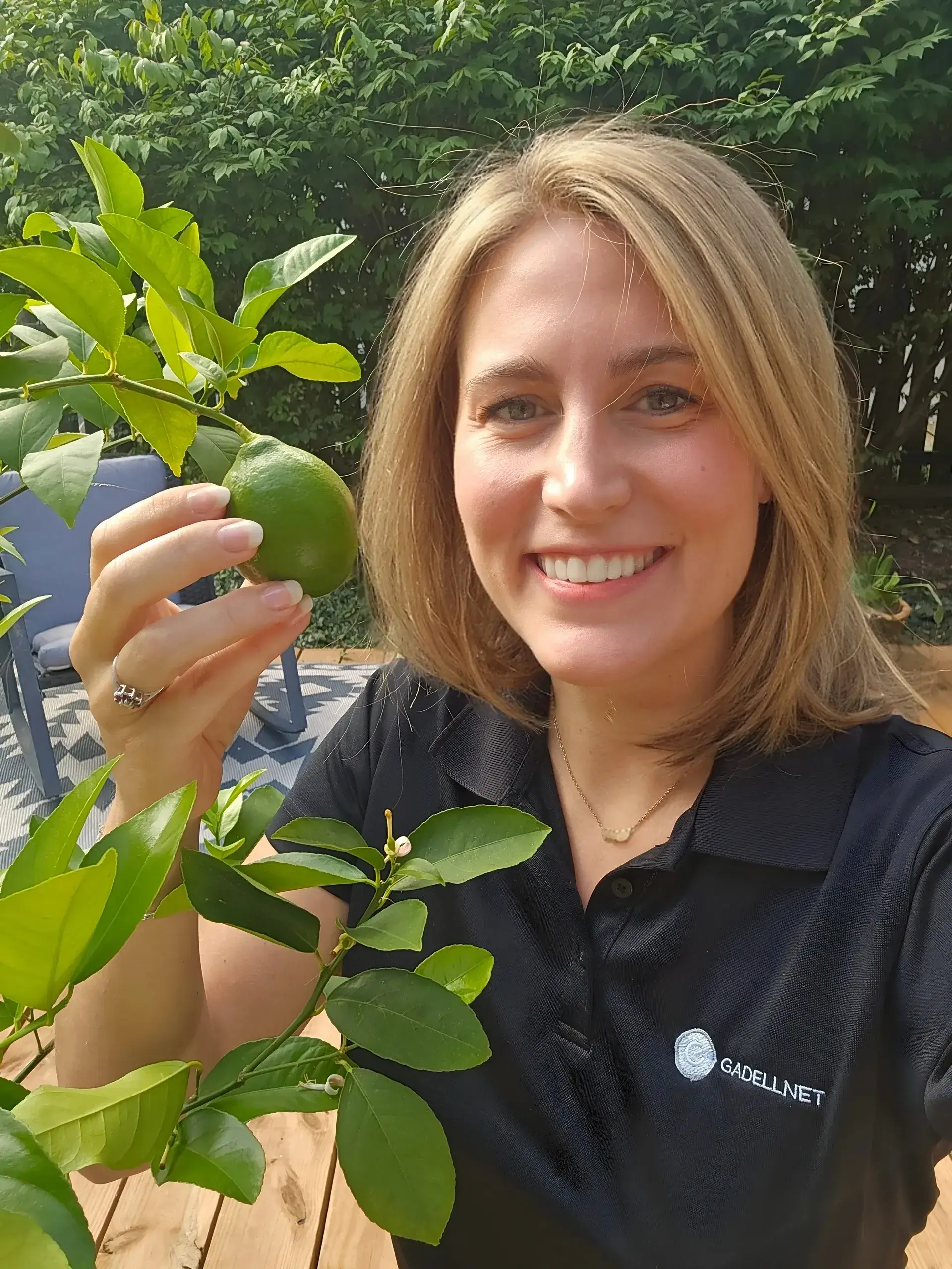 Woman smiling, holding a green fruit.