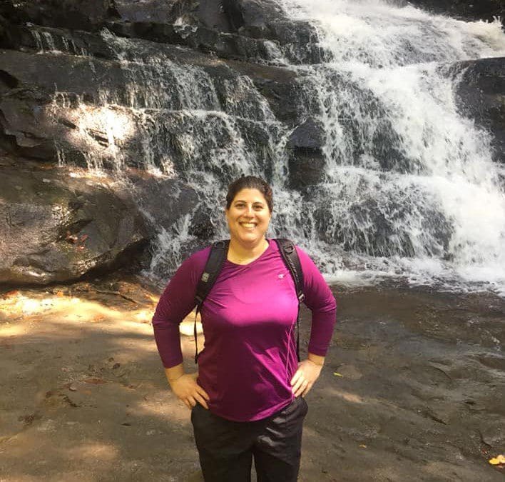 Person smiling in front of a waterfall.